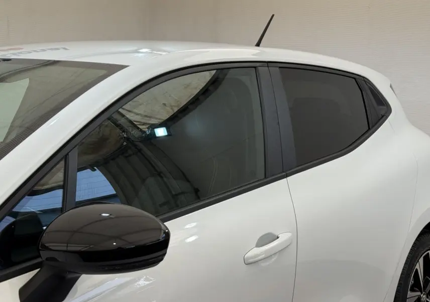 Vue latérale gauche d'une Renault Clio Evolution TCe 100 GPL blanche avec rétroviseur noir brillant et vitres teintées.