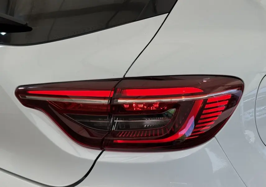 Feu arrière droit allumé sur Renault Clio blanc Evolution TCe 100 GPL, vue rapprochée du coffre et de la porte arrière.