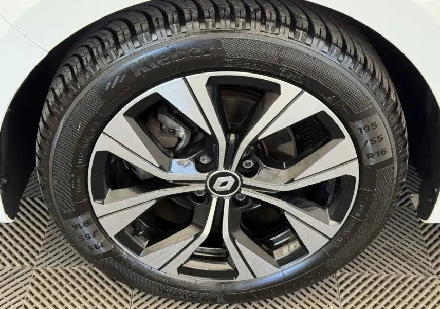 Gros plan sur la roue avant droite d'une Renault Clio blanche avec jante alliage noire et argentée.