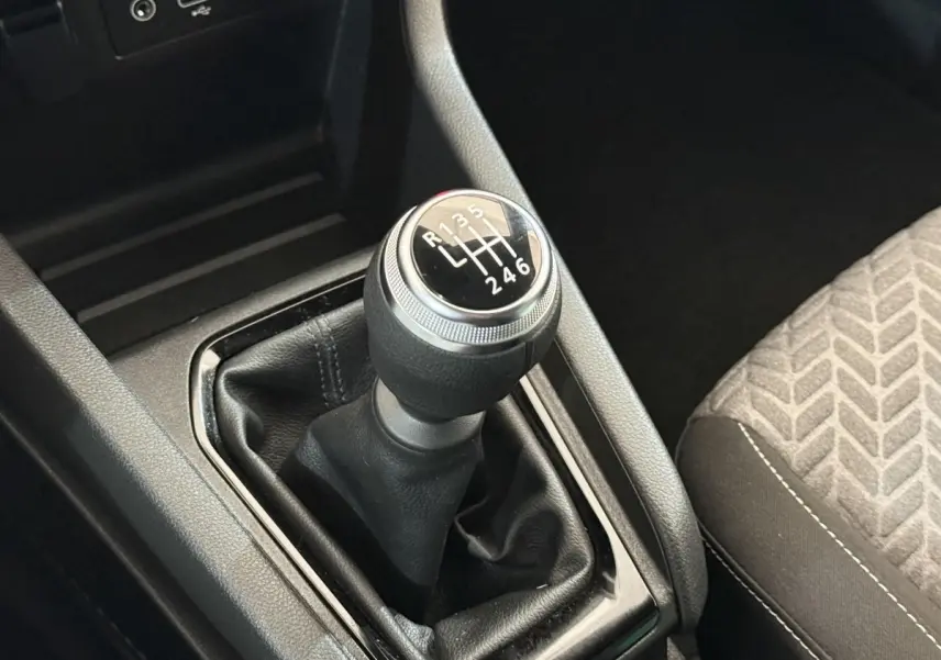 Le levier de vitesses manuel noir de la Renault Clio Evolution TCe 100 GPL, avec console et siège tissu gris à motifs.