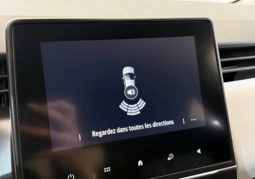 Écran tactile central affichant l'alerte de détection d'obstacles dans une Renault Clio blanche, vue intérieure.