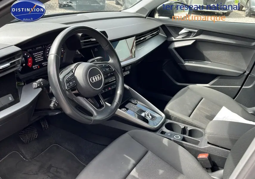 Intérieur avant de l'Audi A3 Sportback 2023 en gris, vue côté conducteur montrant le volant multifonction et la console centrale.