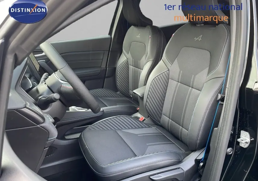 Intérieur du Renault Captur E-Tech hybride 2025, sièges avant noirs avec surpiqûres bleues et logo Alpine brodé.