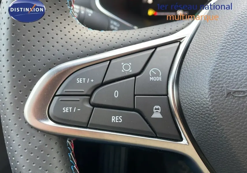 Gros plan sur les commandes du volant en cuir noir perforé du Renault Captur E-Tech hybride 2025, côté gauche.