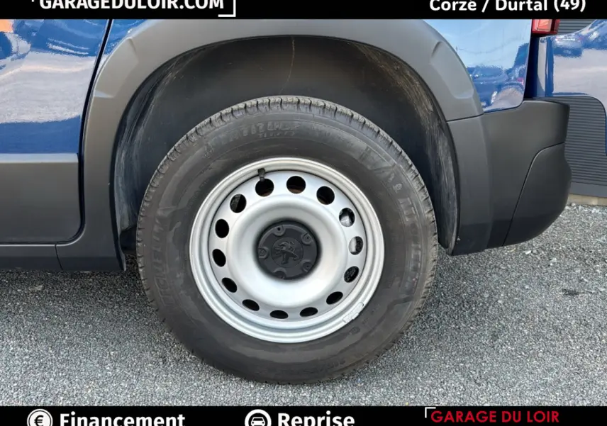 Gros plan sur la roue arrière droite du Peugeot Rifter bleu 2024 avec jante acier et logo Peugeot au centre.