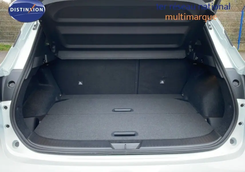 Coffre ouvert en vue arrière d’un Nissan Qashqai blanc nacré, montrant un espace de chargement plat et spacieux.