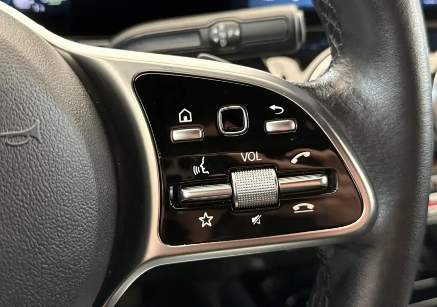 Gros plan sur les commandes du volant cuir noir d’une Mercedes GLA 250 e Business Line 2021, avec molette volume.