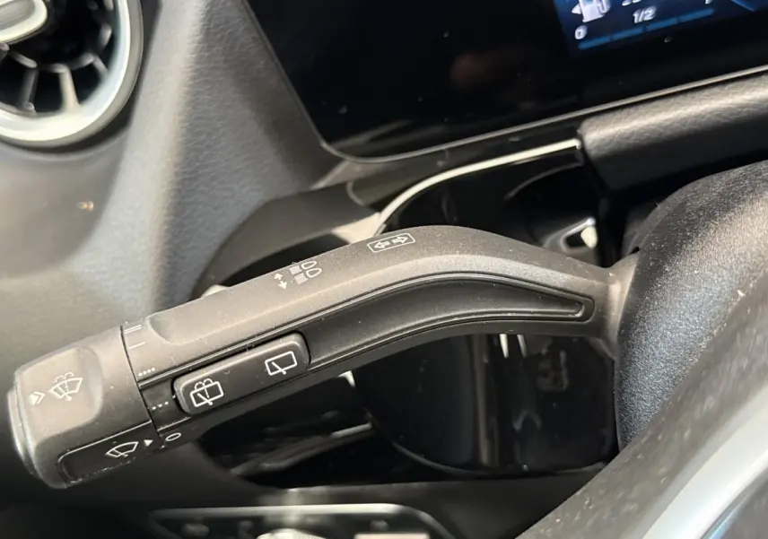 Gros plan sur la commande de essuie-glaces à gauche du volant dans l’habitacle noir du Mercedes GLA bleu 2021.