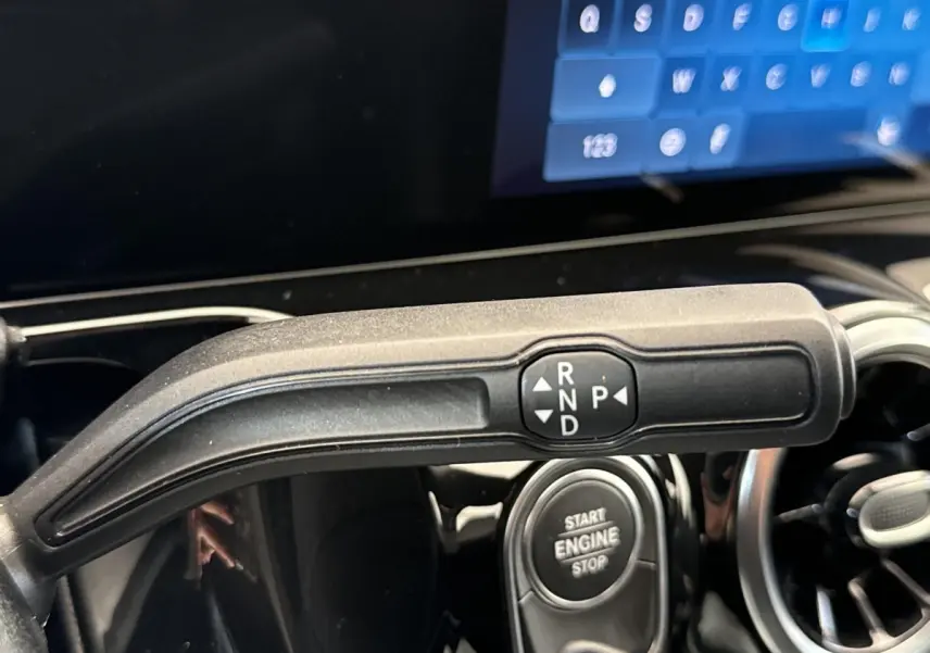 Gros plan sur la commande de boîte automatique et bouton start/stop dans l’habitacle d’un Mercedes GLA bleu.