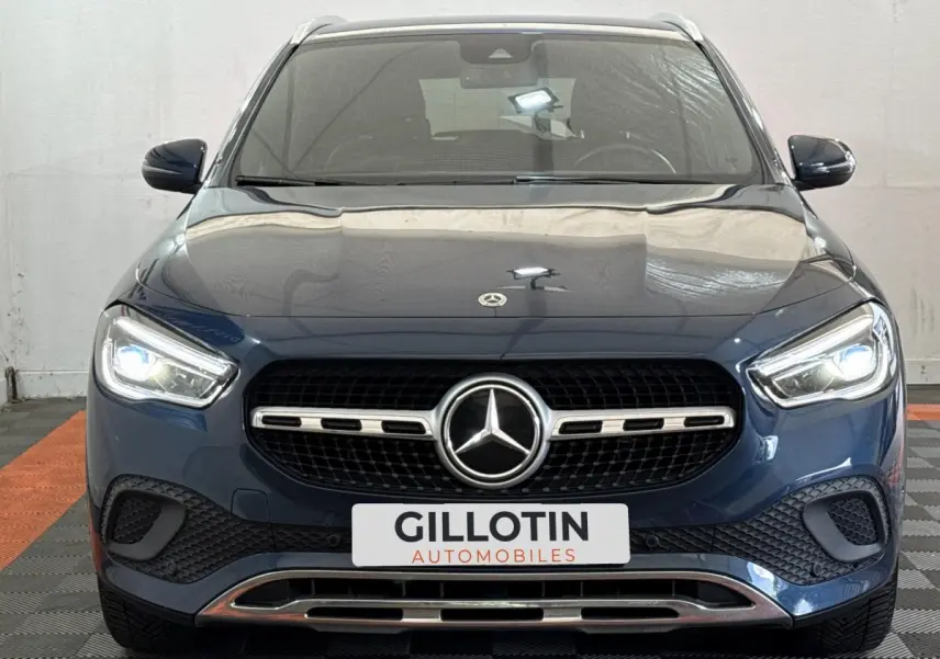 Vue frontale d’un Mercedes GLA 250 e Business Line bleu avec calandre chromée et phares LED allumés.