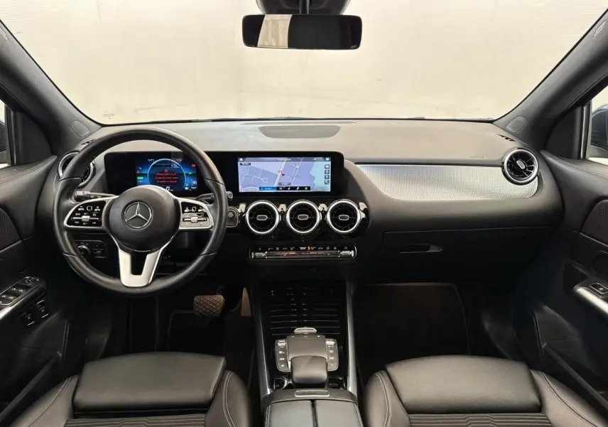 Vue intérieure avant du tableau de bord noir du Mercedes GLA 250 e Business Line avec écran tactile et volant cuir multifonctions.