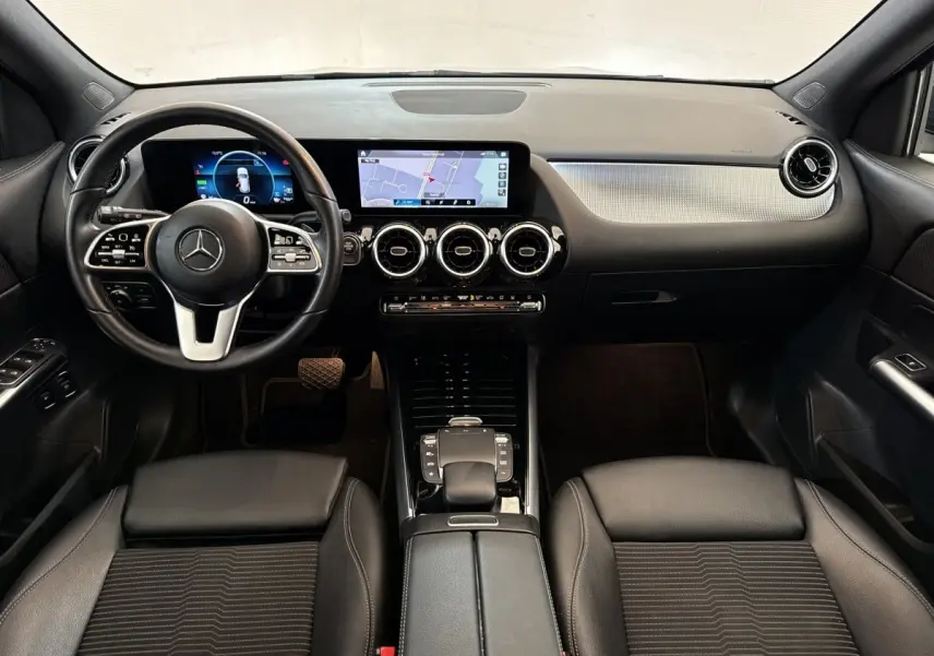 Vue intérieure avant du tableau de bord et volant cuir noir du Mercedes GLA 250 e Business Line 2021 avec écran tactile et navigation.