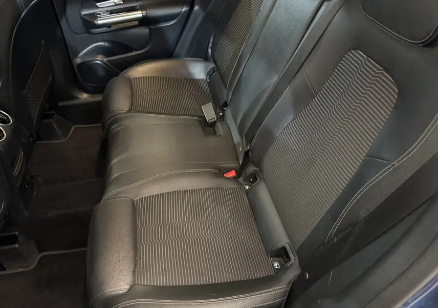 Vue intérieure côté gauche montrant la banquette arrière noire avec inserts tissu et ceinture de sécurité d’une Mercedes GLA 250 e bleu.