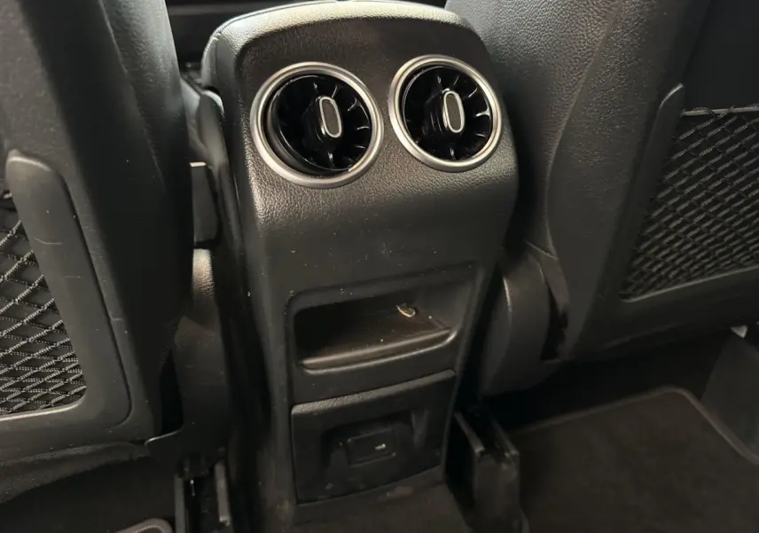 Vue rapprochée des aérateurs arrière et prise USB sur la console centrale noire du Mercedes GLA bleu 2021.