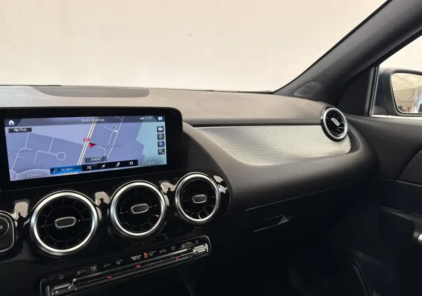 Vue intérieure côté passager du tableau de bord noir et argent avec écran tactile et aérateurs ronds chromés d’une Mercedes GLA 250 e bleu.