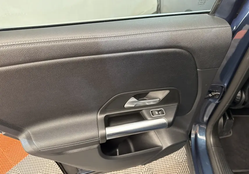 Intérieur de la porte côté gauche d’un Mercedes GLA 250 e Business Line bleu, avec poignée argentée et bouton de verrouillage.