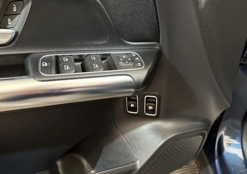 Gros plan sur la porte avant gauche du Mercedes GLA bleu, avec commandes de vitres et rétroviseurs électriques.