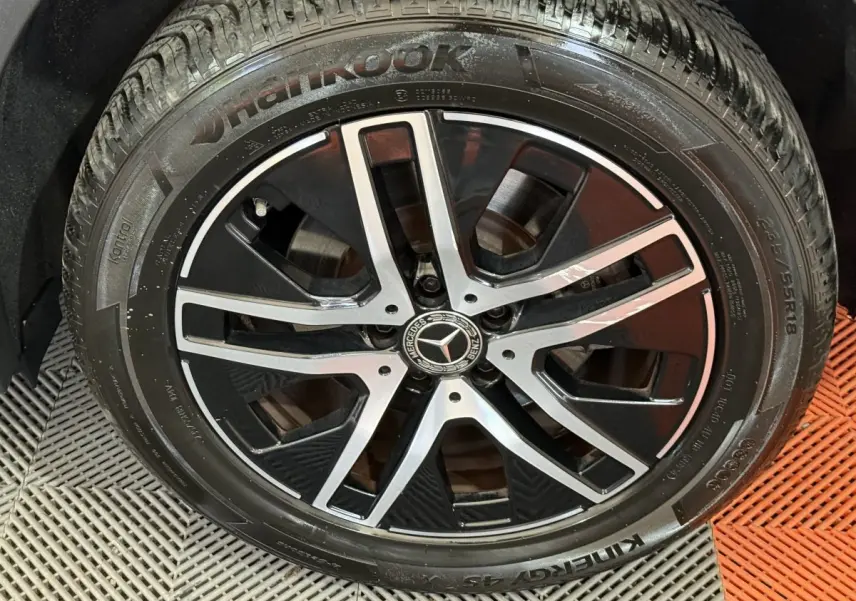 Gros plan sur la jante alliage noire et argentée avec logo Mercedes, montée sur pneu Hankook du Mercedes GLA bleu.
