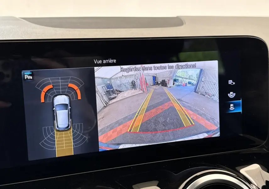 Écran tactile intérieur montrant la caméra de recul et l’aide au stationnement du Mercedes GLA bleu 3/4 arrière.