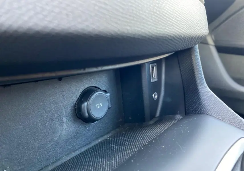 Prise 12V et port USB en gros plan sur la console centrale intérieure de la Peugeot 308 gris aluminium.
