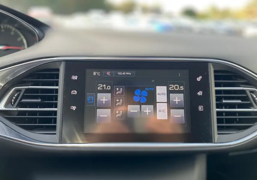 Écran tactile central de la Peugeot 308 gris aluminium 2016 affichant la climatisation automatique bi-zone.