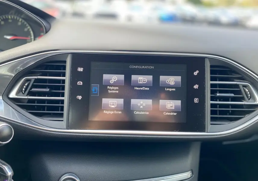 Écran tactile central de la Peugeot 308 gris aluminium, vue frontale du tableau de bord avec commandes visibles.