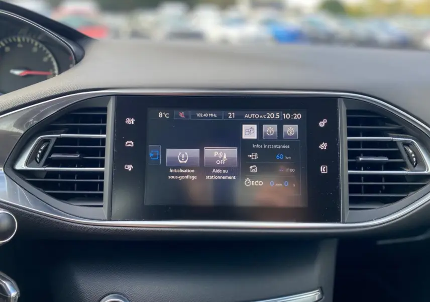 Écran tactile central du tableau de bord de la Peugeot 308 2016 avec affichage des aides au stationnement et température extérieure.