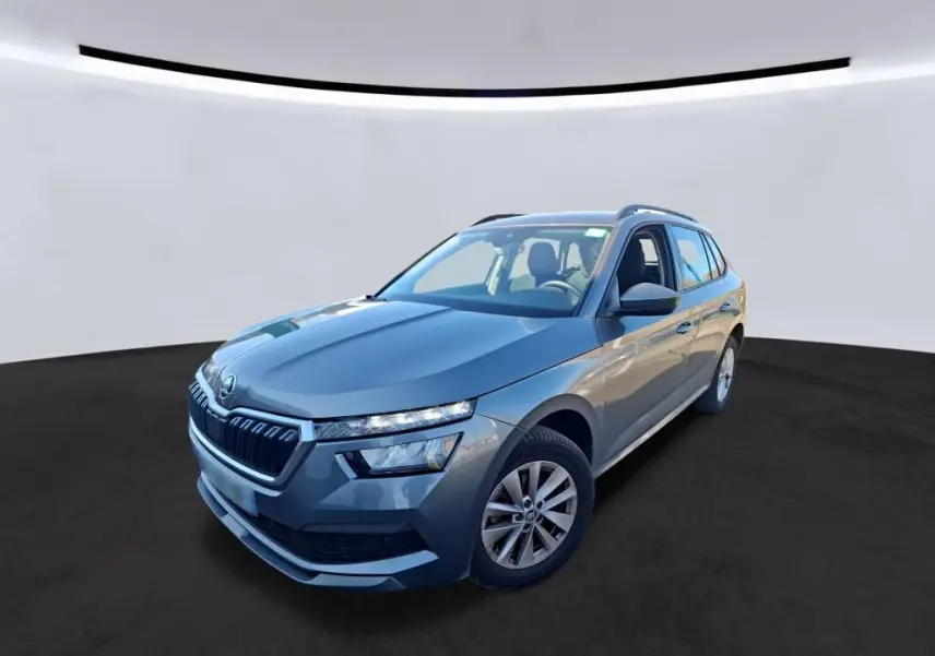 Vue 3/4 avant droite d'un Skoda Kamiq gris foncé 2023 avec calandre distinctive et toit ouvrant visible.