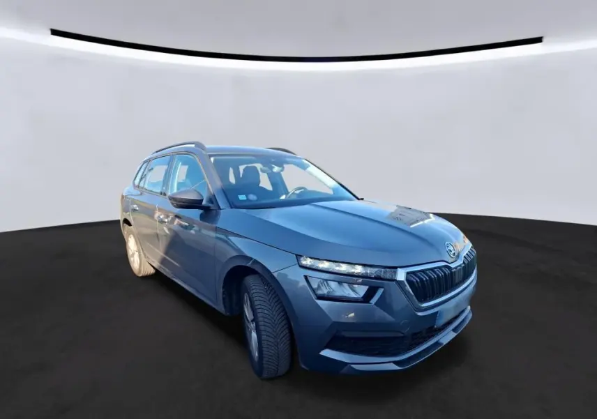 Vue 3/4 avant droit d'une Skoda Kamiq gris foncé 2023 avec calandre distinctive et phares LED fins.