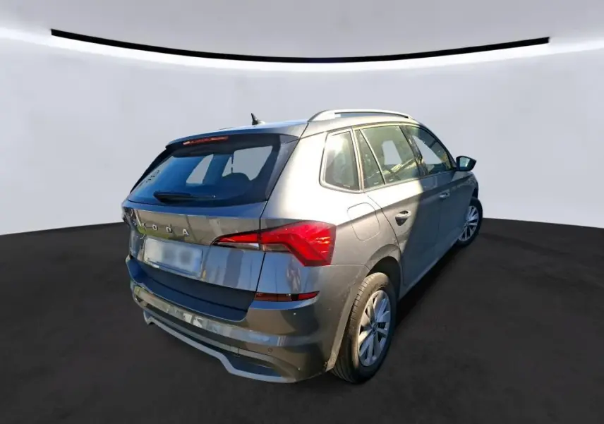 Vue 3/4 arrière droite d'un Skoda Kamiq gris foncé 2023 avec toit ouvrant et feux arrière LED distinctifs.