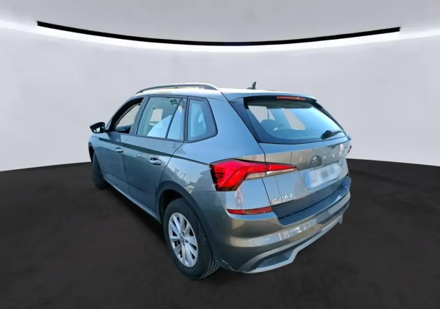 Vue 3/4 arrière droite d'un Skoda Kamiq gris foncé 2023, compact avec feux arrière LED et toit avec barres de toit.