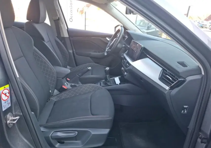 Intérieur avant droit du Skoda Kamiq gris foncé 2023, sièges tissu noir avec surpiqûres et tableau de bord moderne.