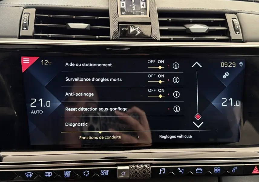 Écran tactile central du DS7 Crossback gris foncé montrant les réglages d’aide à la conduite et la climatisation à 21°C.