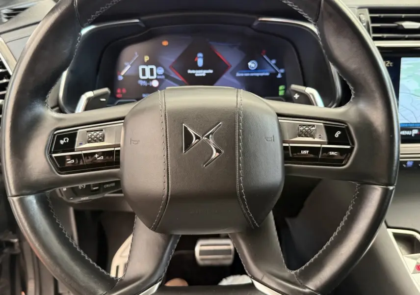 Vue rapprochée du volant cuir noir de la DS7 Crossback avec tableau de bord numérique et commandes intégrées.
