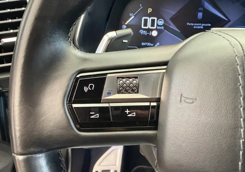 Gros plan sur le volant cuir noir côté gauche du DS7 Crossback avec commandes vocales et tableau de bord numérique.