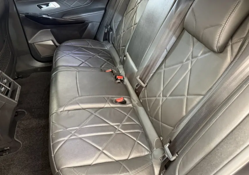 Vue rapprochée de la banquette arrière en cuir noir matelassé du DS7 Crossback gris foncé, avec ceintures et porte-gobelets.