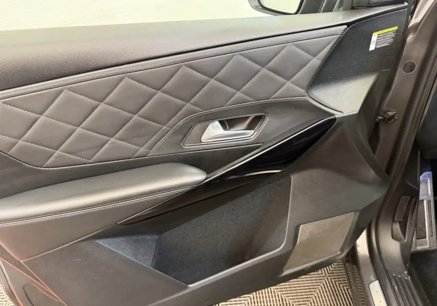 Gros plan sur la porte intérieure côté conducteur du DS7 Crossback gris foncé avec surpiqûres losanges et insert noir brillant.