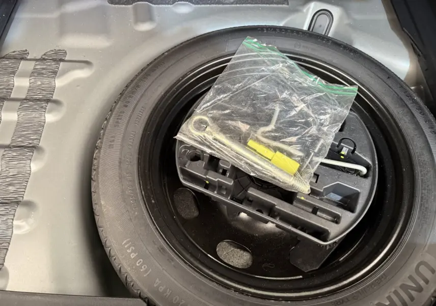 Gros plan sur la roue de secours et le kit d’outils dans le coffre d’un DS7 Crossback gris foncé.