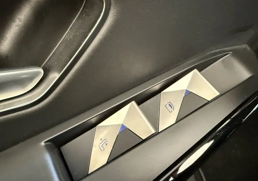 Gros plan sur les commandes de réglage des sièges en métal brossé dans une DS7 Crossback gris foncé.