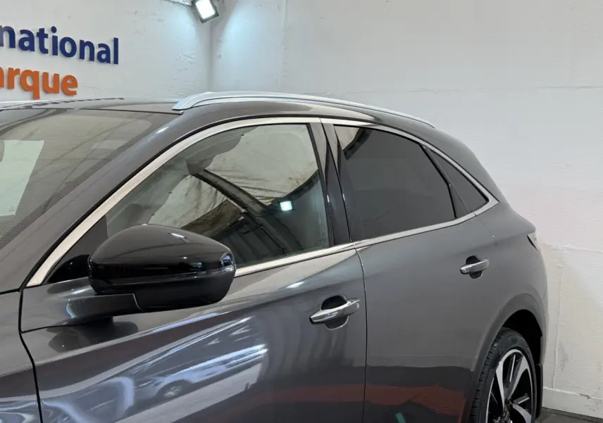 Vue côté gauche du DS7 Crossback gris foncé, mettant en valeur les vitres teintées et les jantes alliage noires.