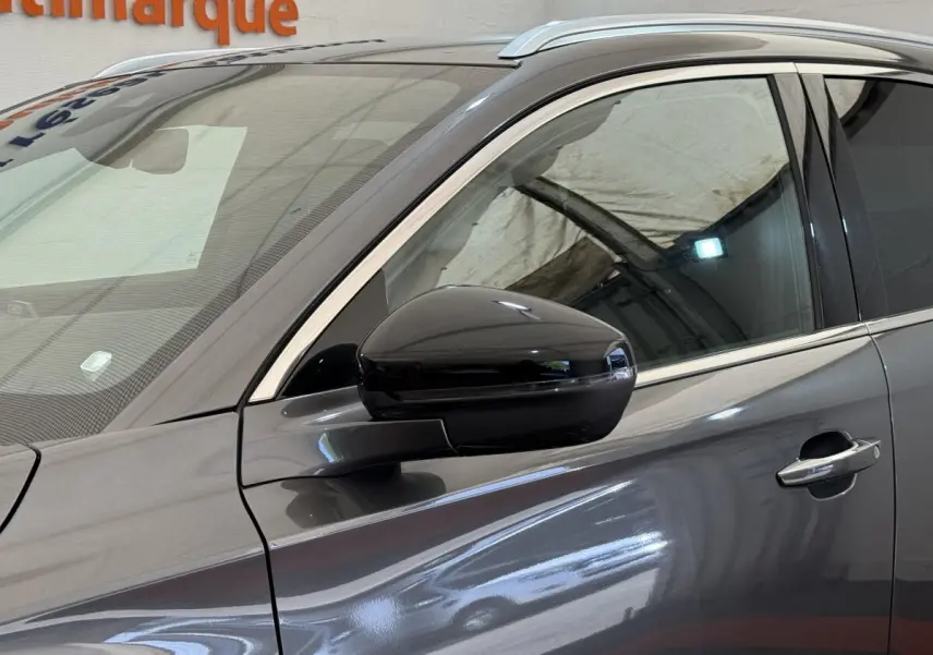 Vue côté gauche rapprochée du DS7 Crossback gris foncé, mettant en valeur la vitre teintée et le rétroviseur noir brillant.