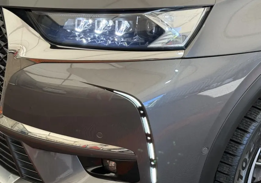 Gros plan sur l’avant droit gris foncé du DS7 Crossback avec phares LED et feux diurnes verticaux allumés.