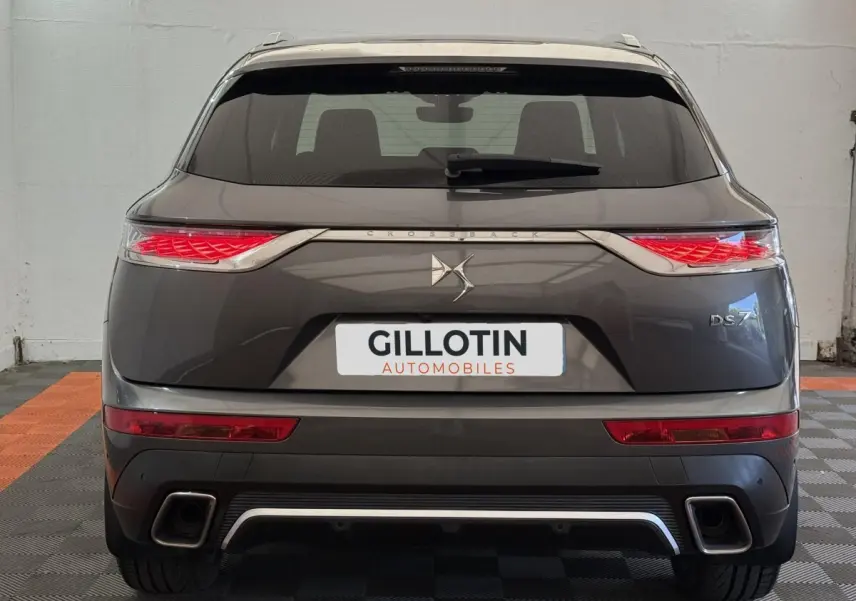 Vue arrière d'un DS7 Crossback gris foncé avec feux arrière LED distinctifs et double sortie d'échappement.