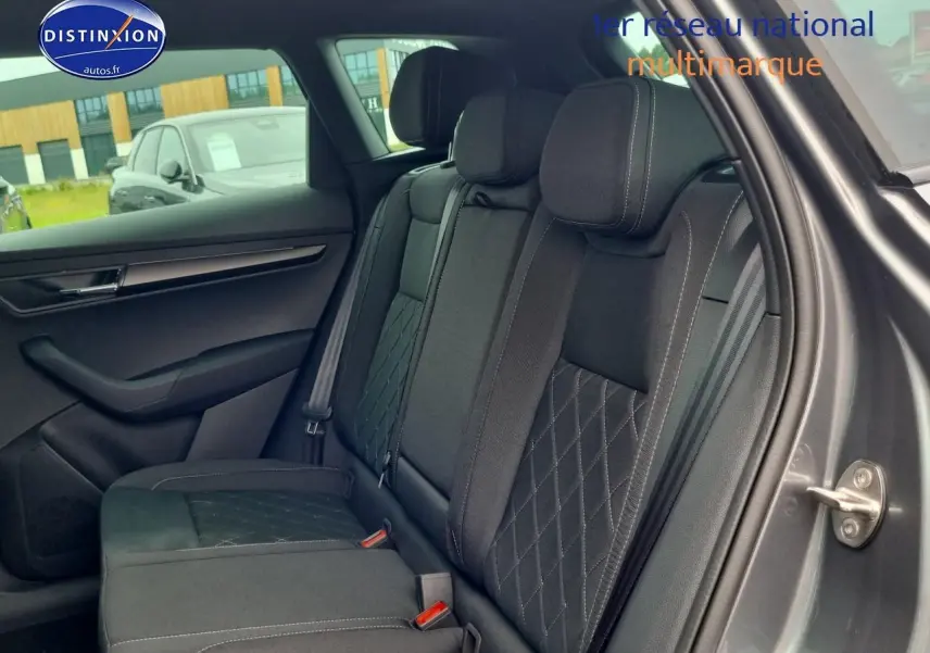 Vue latérale droite de l'intérieur arrière du Skoda Karoq gris graphite avec sièges tissu noir à surpiqûres croisées.