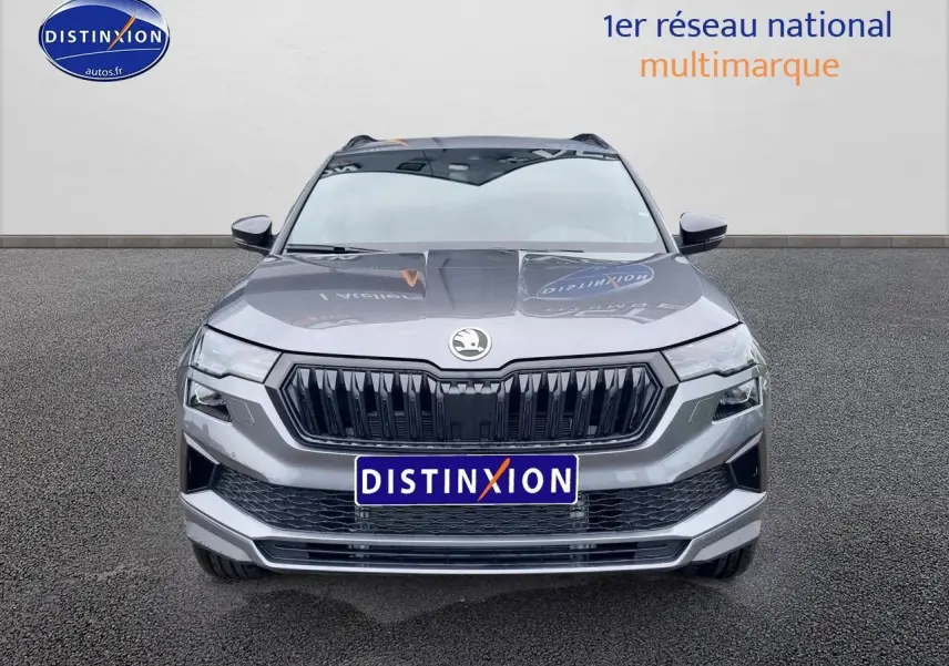 Vue frontale d'un SUV SKODA KAROQ gris graphite avec calandre noire et logo centré sur fond neutre.