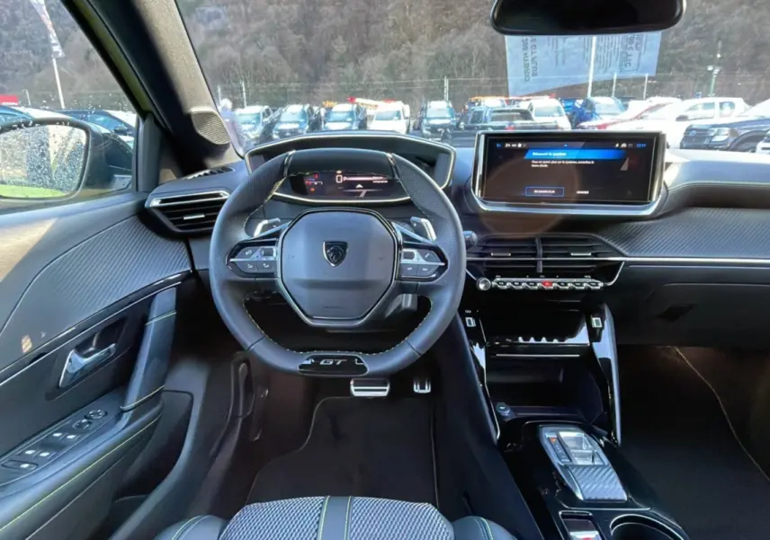 Intérieur du Peugeot 208 Hybrid 136 GT Plus 2024, vue frontale du poste de conduite avec volant compact et écran tactile.