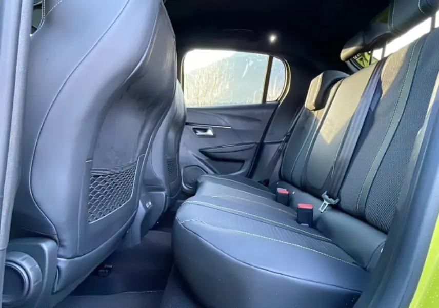 Vue intérieure arrière droite des sièges noirs avec surpiqûres vertes du Peugeot 208 Hybrid 136 GT Plus 2024.