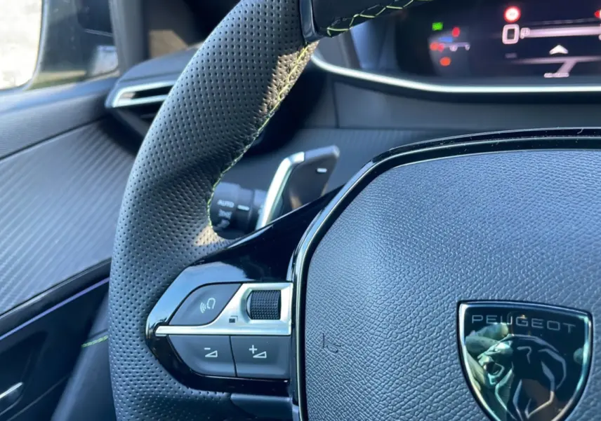 Gros plan sur le volant perforé et les commandes du côté gauche du Peugeot 208 Hybrid 136 GT Plus 2024.