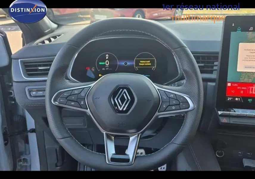 Vue rapprochée du volant multifonction noir avec logo Renault et tableau de bord numérique du Captur E-Tech hybride.