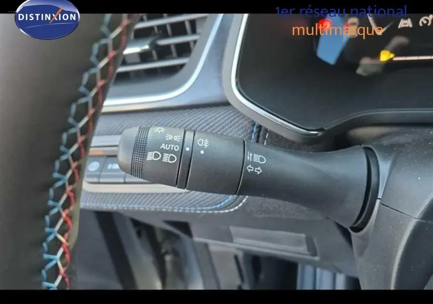 Gros plan sur la commande des feux à gauche du volant du Renault Captur gris rafale, intérieur avec surpiqûres colorées.